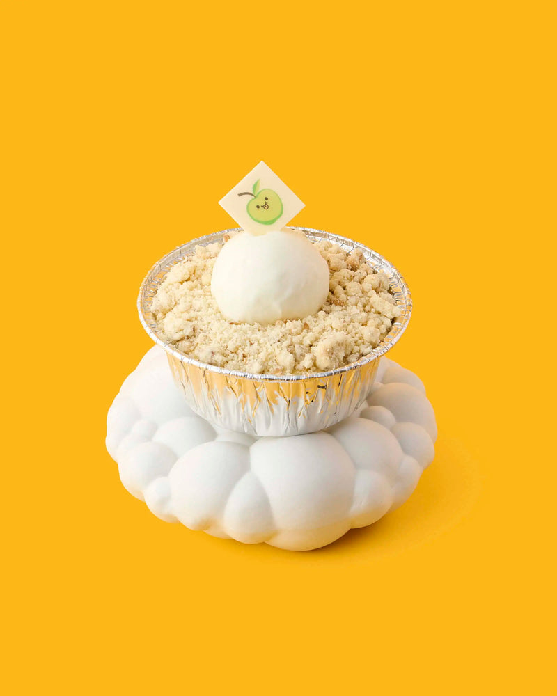 GLO Pasticceria dessert cupcake with crumbly topping and white cream on a cloud-shaped stand against a yellow background