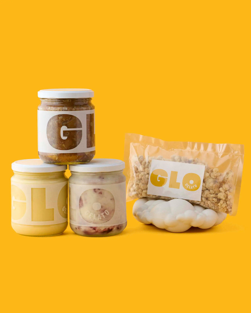 GLO Foods product assortment with three glass jars of spreads, a granola pouch, and cloud-shaped crackers on a yellow background